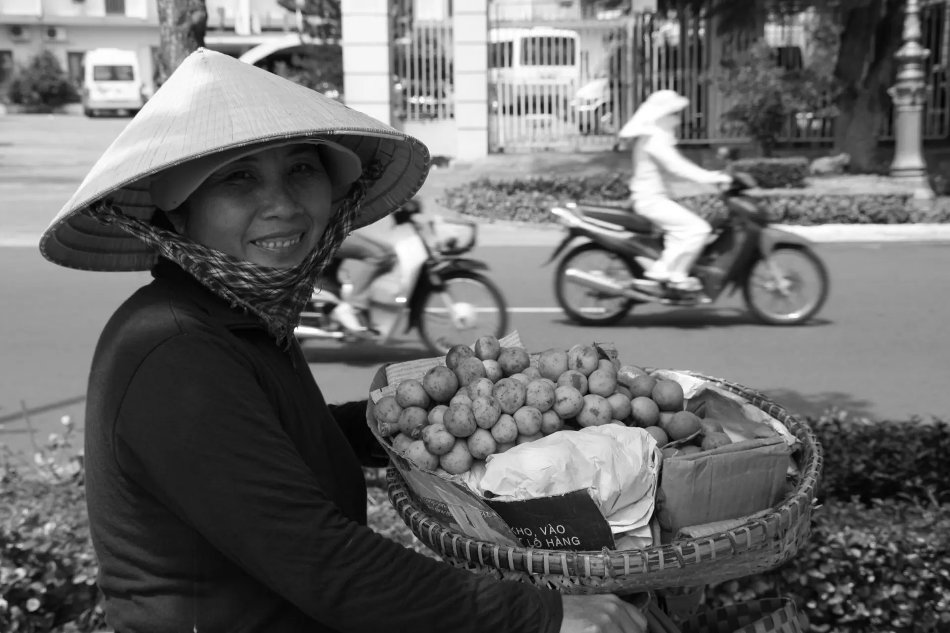 Marchande de fruits coiffée du chapeau conique, dans une rue vietnamienne